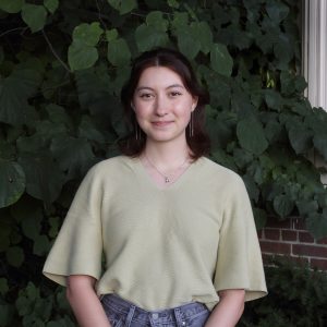 Rebecca Denhart poses for photo in front of dark green vegetation.